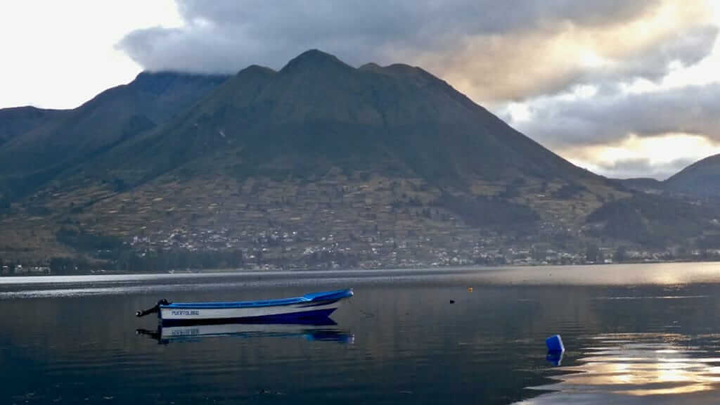 Ein Boot schwimmt auf dem San Pablo Lake vor der Kulisse des Vulkans Imbabura